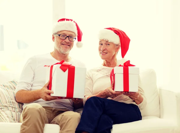Felice coppia di anziani in cappelli di Babbo Natale con scatole regalo — Foto Stock