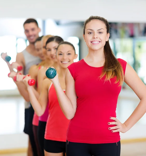 Groep lachende mensen met halters in de sportschool — Stockfoto