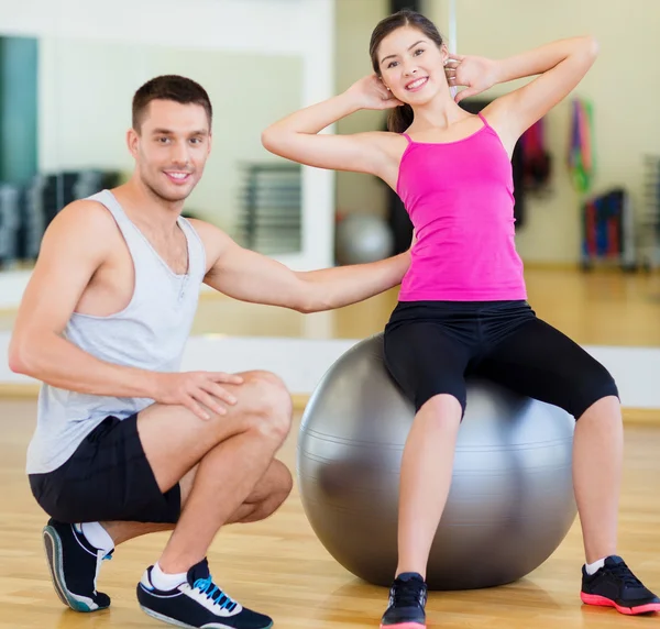 Treinador masculino com mulher fazendo crunches na bola — Fotografia de Stock