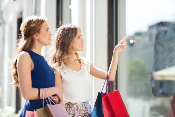 Mulheres felizes com sacos de compras na vitrine da loja — Fotografia de Stock
