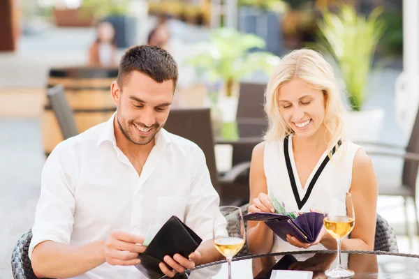 Happy couple with wallet paying bill at restaurant — Stock Photo, Image