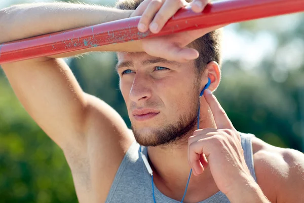 Young man with earphones and horizontal bar — Stock Photo, Image