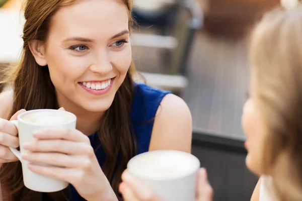 Mujeres jóvenes sonrientes con tazas de café en la cafetería —  Fotos de Stock