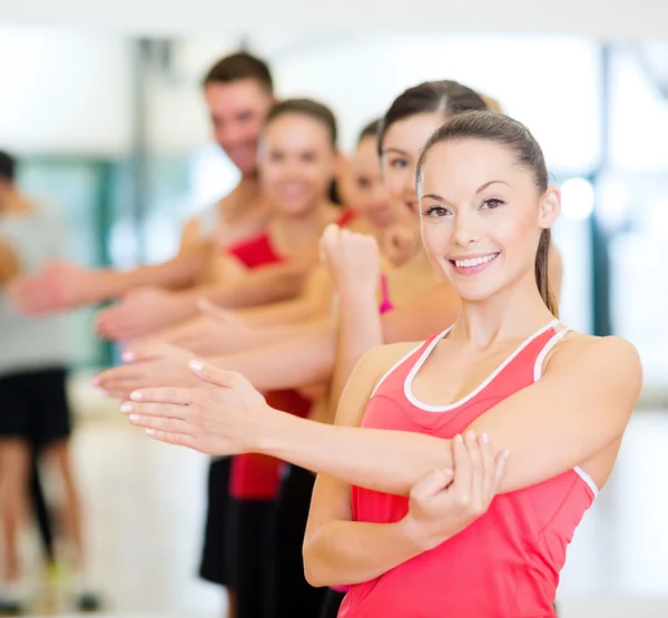 Groep glimlachende mensen die zich uitstrekt in de sportschool — Stockfoto