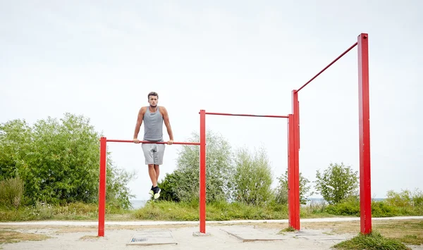 Jongeman die buiten op de horizontale balk traint — Stockfoto