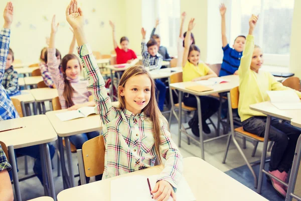 Gruppo di scolari alzare le mani in classe — Foto Stock