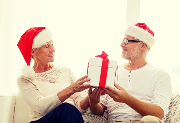 Счастливая старшая пара в шляпах Санты с подарочной коробкой — стоковое фото