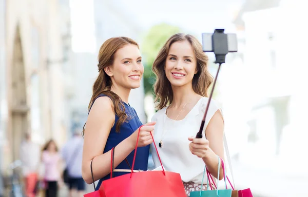 Mulheres felizes com sacos de compras e smartphone — Fotografia de Stock