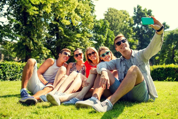 Amigos sonrientes con teléfono inteligente haciendo selfie —  Fotos de Stock