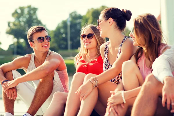 Group of smiling friends sitting on city street — Stock Photo, Image