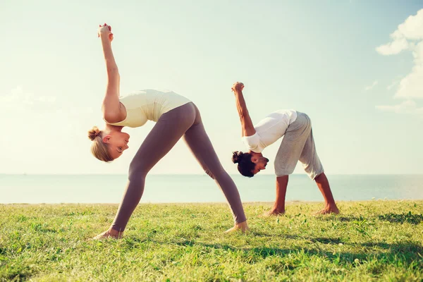 Pareja sonriente haciendo ejercicios de yoga —  Fotos de Stock