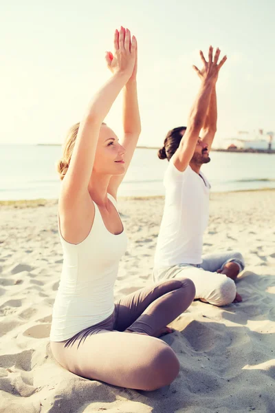 Pareja sonriente haciendo ejercicios de yoga — Foto de Stock