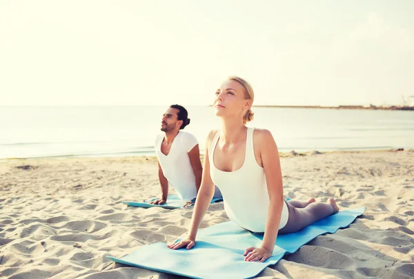 Coppia fare esercizi di yoga all'aperto — Foto Stock