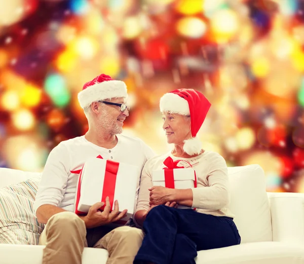 Glückliches Seniorenpaar in Weihnachtsmützen mit Geschenkschachteln — Stockfoto