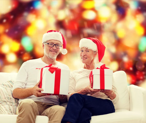 Felice coppia di anziani in cappelli di Babbo Natale con scatole regalo — Foto Stock