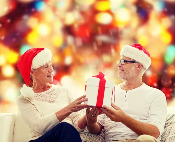 Heureux couple aîné dans chapeaux Santa avec boîte cadeau — Photo