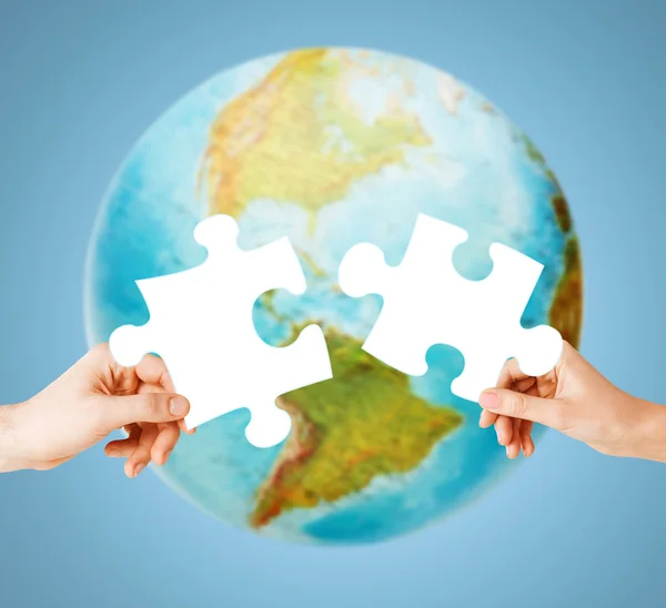 Hands with white blank puzzle over earth globe — Stock Photo, Image