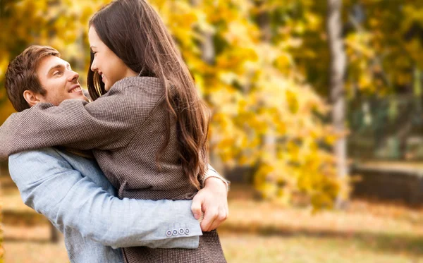 Sonriente pareja abrazándose sobre el fondo de otoño — Foto de Stock