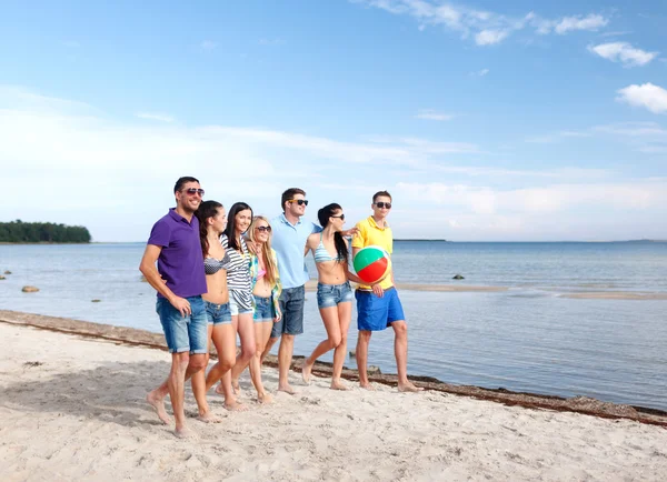 Groep gelukkige vrienden wandelen langs strand — Stockfoto