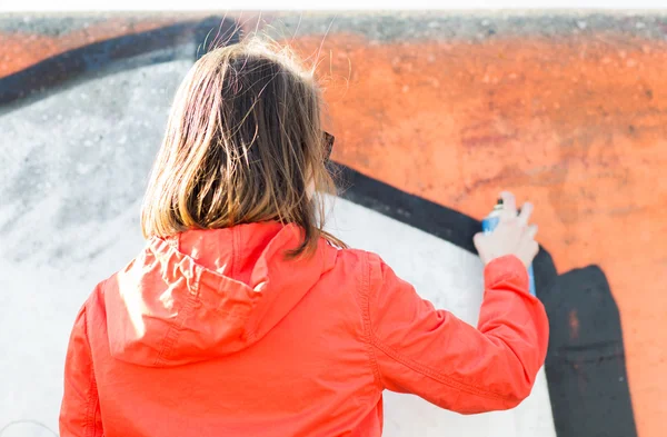 Mujer dibujando graffiti con pintura en aerosol desde atrás — Foto de Stock
