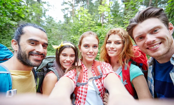 Amigos con mochila tomando selfie en madera — Foto de Stock