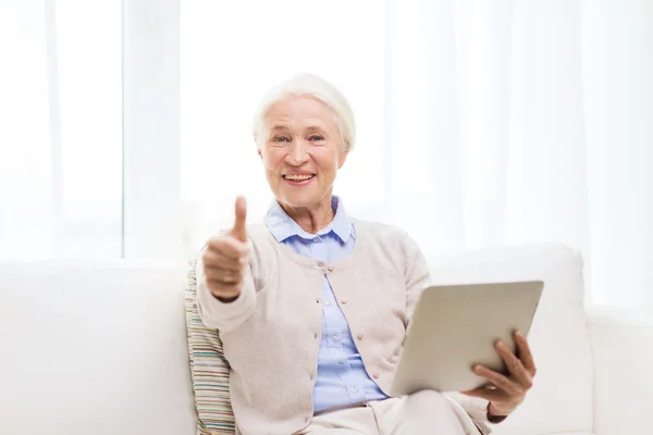 Donna anziana con tablet pc mostrando pollici in su — Foto Stock