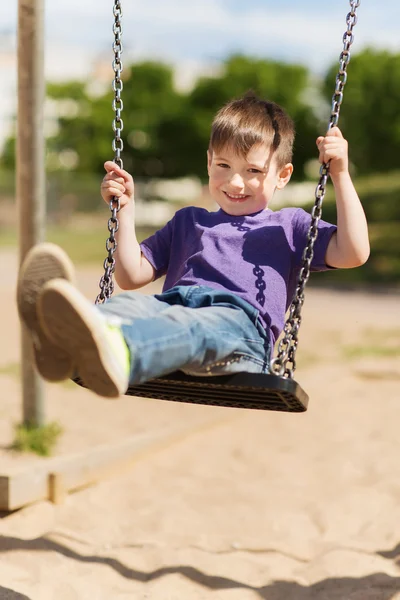 Felice bambino oscillazione su swing al parco giochi — Foto Stock