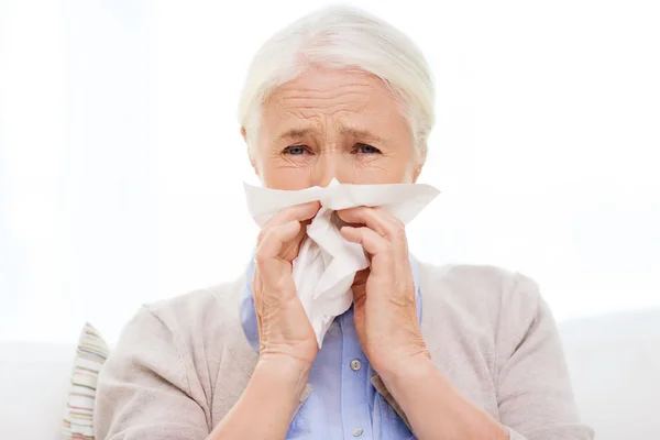 Chory starszy kobieta dmuchanie nosa do papierową serwetkę — Zdjęcie stockowe