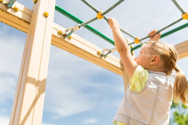 Primer plano de la niña escalando en el parque infantil — Foto de Stock