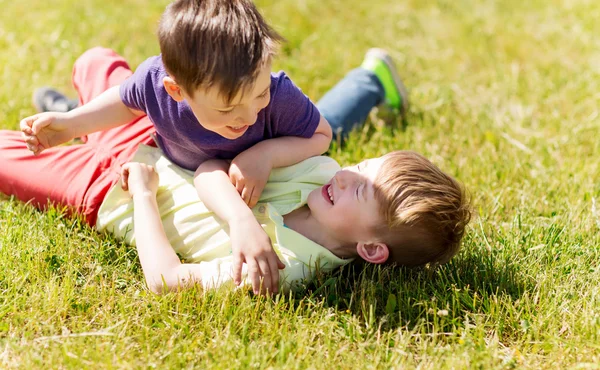 Niños pequeños felices luchando por diversión en la hierba — Foto de Stock