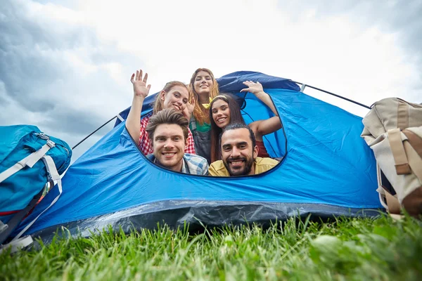 Amigos felizes com mochilas na barraca no acampamento — Fotografia de Stock