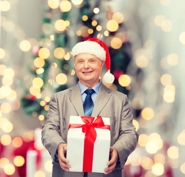 Χαμογελαστός άνθρωπος στο κοστούμι και santa καπέλο βοηθός με δώρο — Φωτογραφία Αρχείου