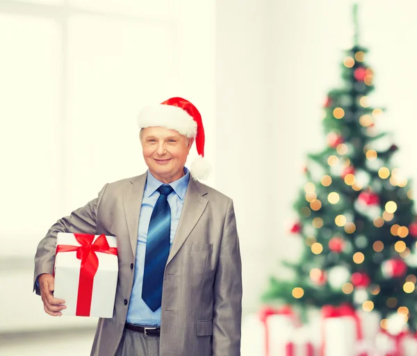 Hombre sonriente en traje y sombrero de ayudante de santa con regalo —  Fotos de Stock