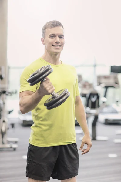 Hombre sonriente con mancuerna en el gimnasio — Foto de Stock