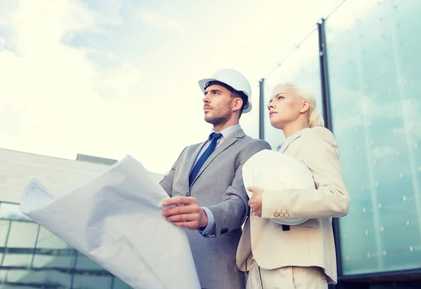 Hombres de negocios con planos y cascos — Foto de Stock