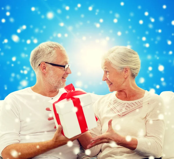 Glückliches Seniorenpaar mit Geschenkbox zu Hause — Stockfoto