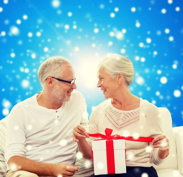 Happy senior couple with gift box at home — Stock Photo, Image