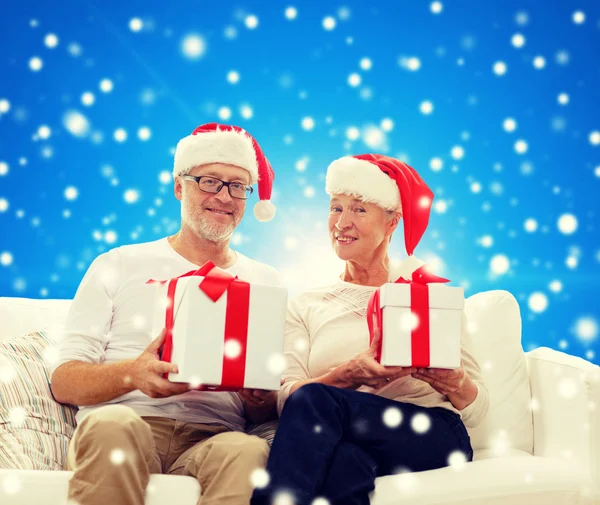 Felice coppia di anziani in cappelli di Babbo Natale con scatole regalo — Foto Stock