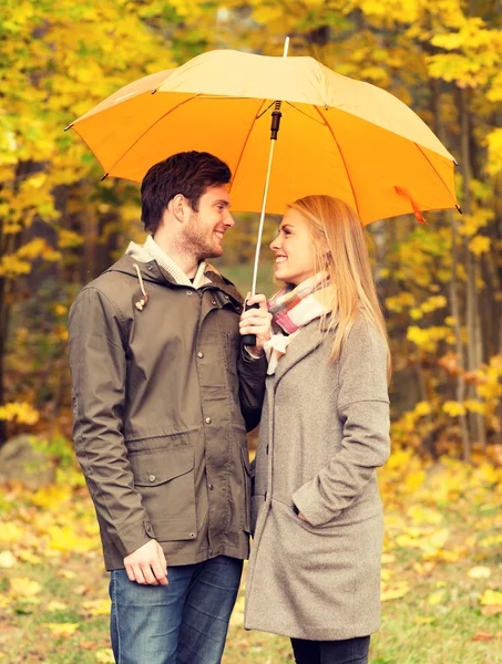 Pareja sonriente con paraguas en el parque de otoño — Foto de Stock