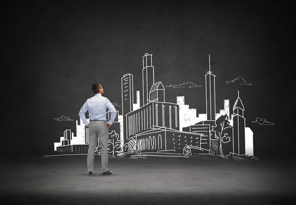 Businessman looking at city drawing — Stock Photo, Image