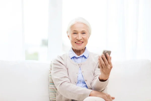 Seniorvrouw met smartphone thuis — Stockfoto