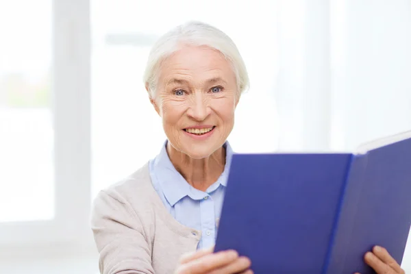 Glücklich lächelnde Seniorin liest Buch zu Hause — Stockfoto