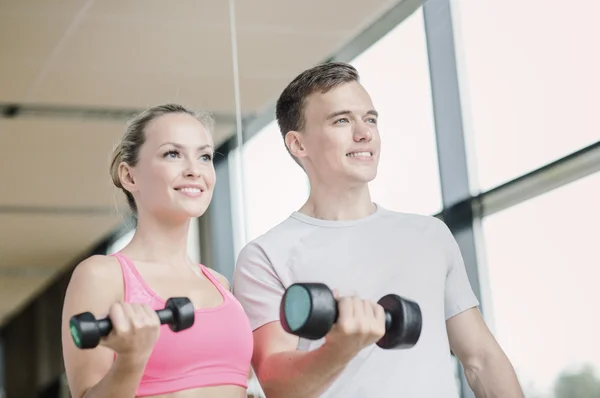 Sonriente joven con entrenador personal en el gimnasio Imágenes De Stock Sin Royalties Gratis