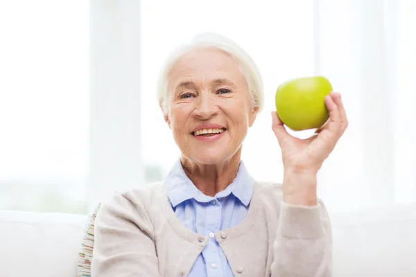 Happy senior woman with green apple at home Royalty Free Stock Photos