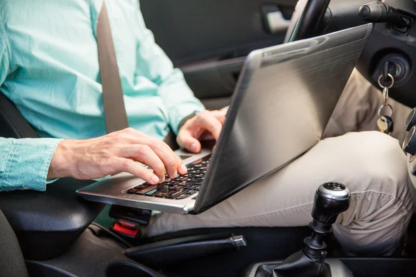 Primo piano di giovane uomo con computer portatile guida auto — Foto Stock