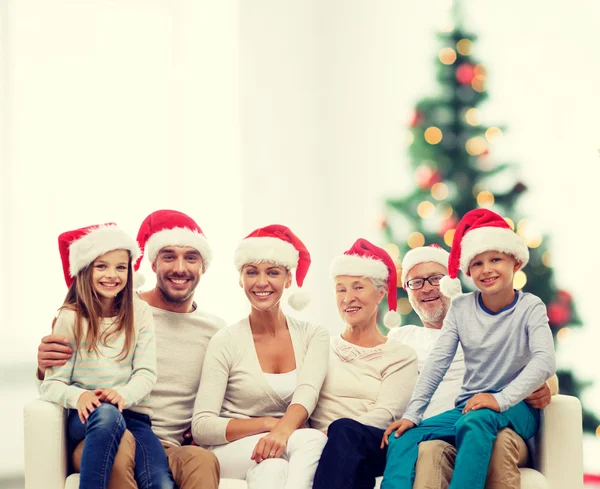 Famiglia felice in cappelli Babbo Natale helper seduto sul divano — Foto Stock