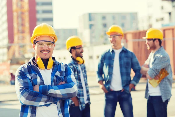 Grupp av leende byggare i hardhats utomhus — Stockfoto