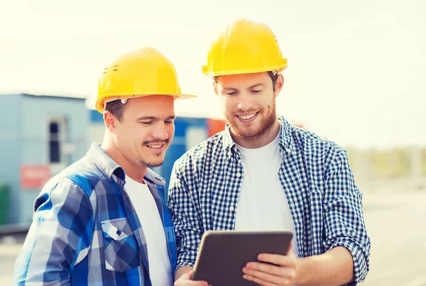 Construtores sorridentes em hardhats com tablet pc — Fotografia de Stock