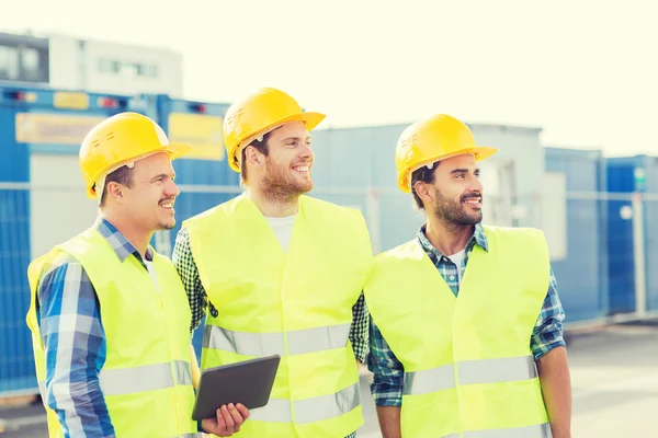 Constructores sonrientes en sombreros con tablet pc —  Fotos de Stock