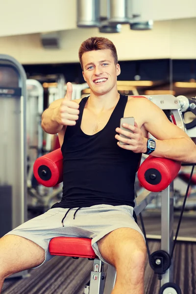 Lächelnder junger Mann mit Smartphone im Fitnessstudio — Stockfoto